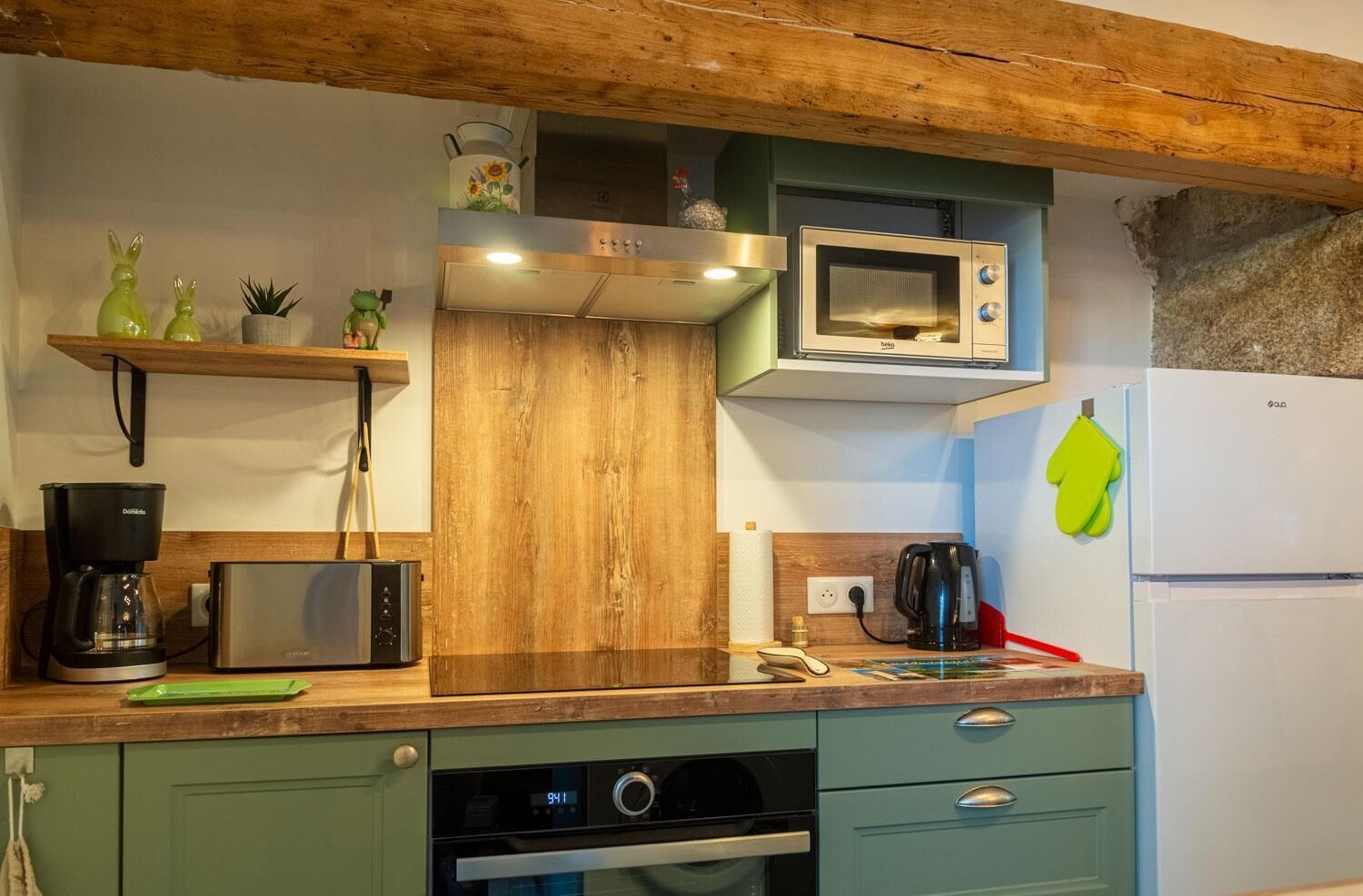 A kitchen with a wooden ceiling, a microwave, a coffee maker, a toaster, and a refrigerator.