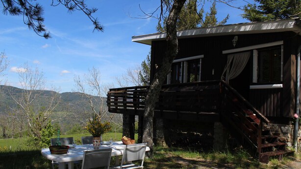 A rustic cabin with a dining table set outdoors, surrounded by natural scenery. - Chalet Gré, between greenery and Cevennes mountains (LE POMPIDOU)