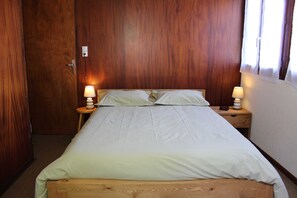 Ein Schlafzimmer mit einem hölzernen Bett, zwei Nachttischlampen und einem Nachttisch aus Holz.