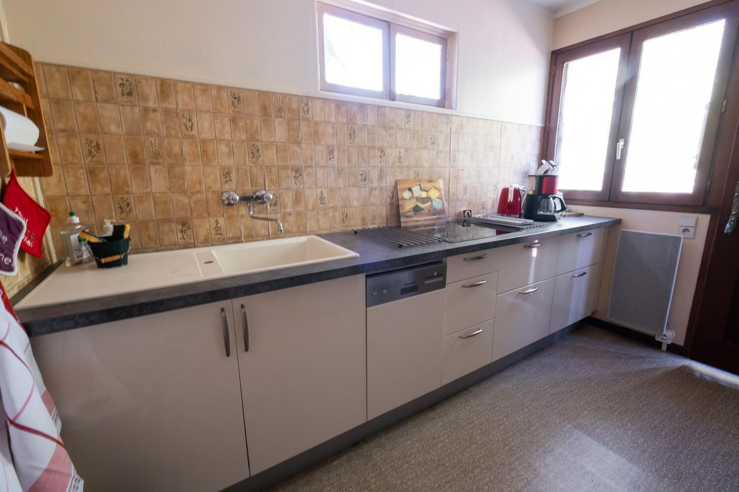 A kitchen with a sink, countertop, cabinets, and a window.
