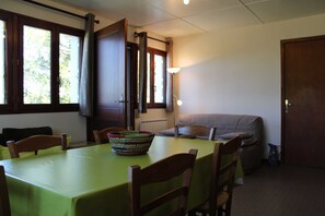 Ein Essbereich mit Tisch, Stühlen, einer Schüssel, einer Couch und einer Tür.