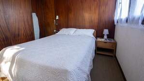 A bedroom with a bed, a nightstand, a lamp, and wooden walls. - Chalet Gré, between greenery and Cevennes mountains (LE POMPIDOU)