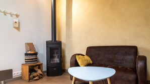 Ein Wohnzimmer mit einer braunen Ledersofa, einem blauen Tisch, einem schwarzen Holzofen und einem Holztisch mit einem gewebten Korb.