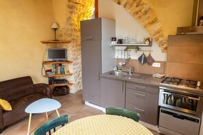 Eine kompakte Küche mit Gasherd, Backofen und einer kleinen Essecke mit Tisch und Stühlen.