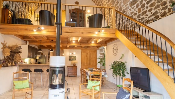 Un salón amplio con techo alto, chimenea, muebles de madera y una escalera.
