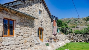 Un edificio de piedra con un pequeño patio, una puerta de madera y una ventana.