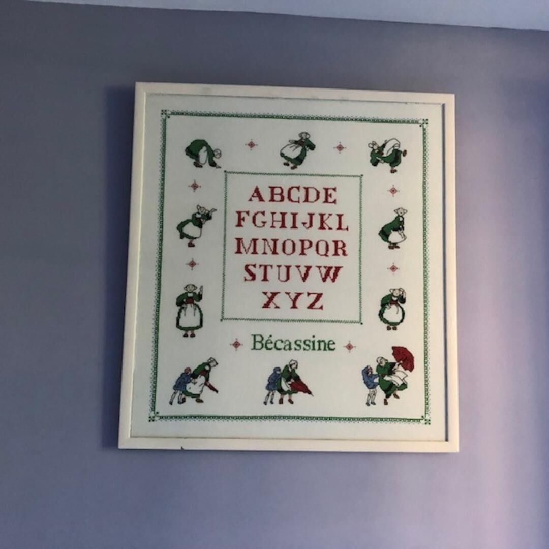 A framed alphabet chart with illustrations of children and the word 'Bécassine' at the bottom.