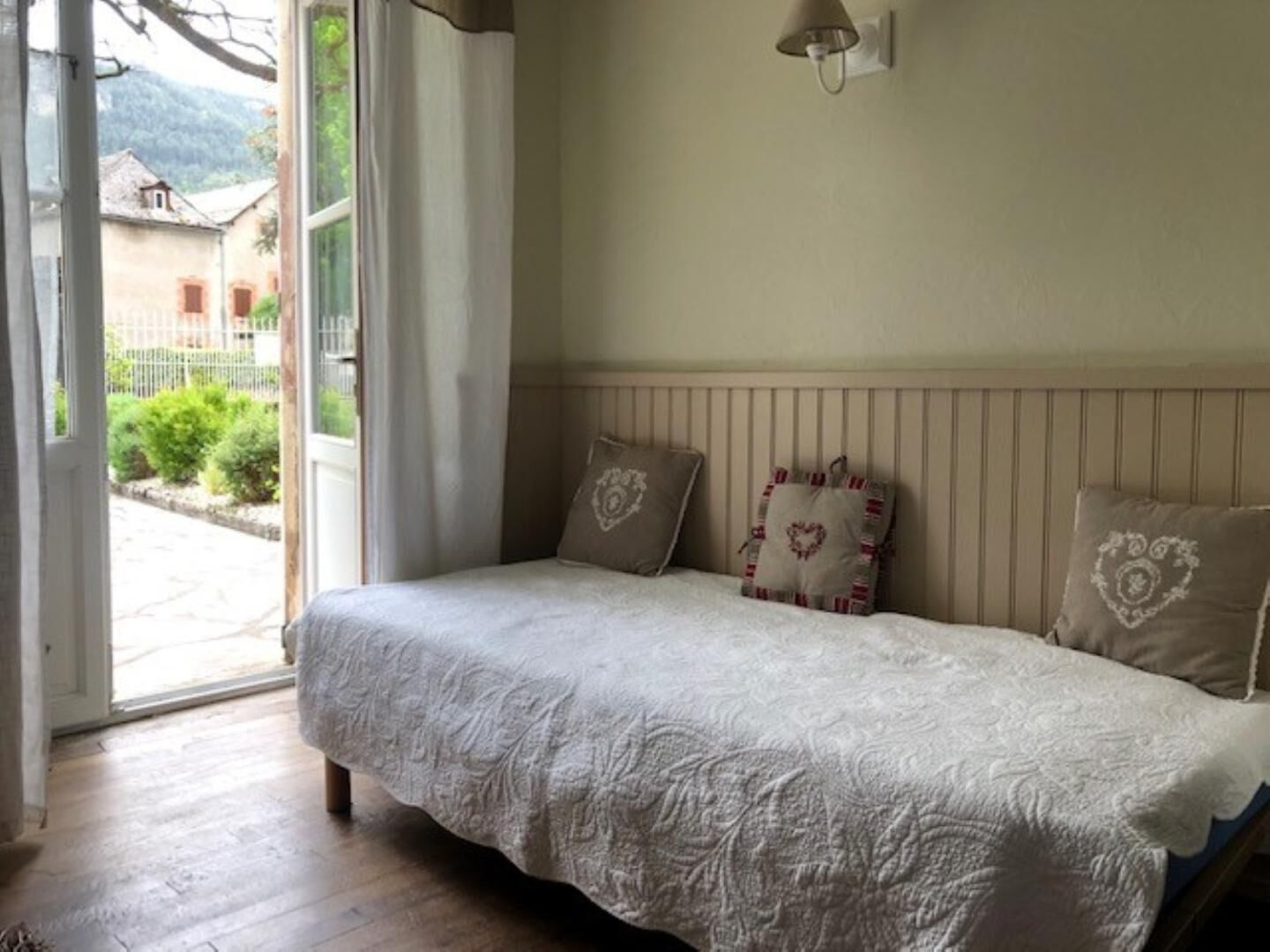 A bedroom with a bed, a window, and a view of the outside.