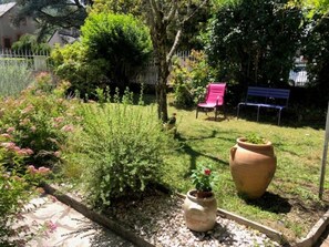 A garden with a variety of plants, a potted plant, a large pot, and a bench. - La Glycine 5/6 persons (LA CANOURGUE)