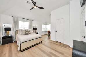 A bedroom with a bed, bedside tables, a ceiling fan, and a door. - Sam Houston Race Track/Garage/Pet friendly/BBQGril (Houston)