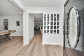 Ein modernes Interieur mit Holzboden, einem Billardtisch und einer Wandvitrine mit Dekorationen.