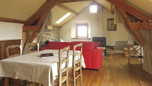 Een loft-achtige kamer met een eettafel, rode bank en een open haard.