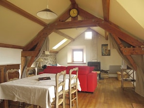Ein Loft-Zimmer mit Esstisch, rotem Sofa und Kamin.