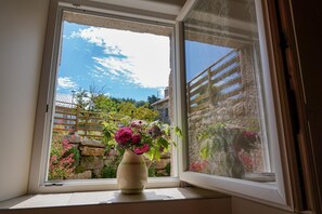 Ein Fenster mit Blick auf einen Garten und eine Steinmauer.