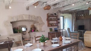 Un comedor rústico con pared de piedra, mesa y sillas de madera.
