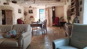 Un interior rústico con suelo de piedra, una zona de comedor y una silla roja.
