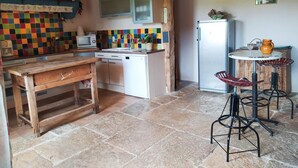 Una cocina con una mesa de madera, lavavajillas, refrigerador y un salpicadero de colores.