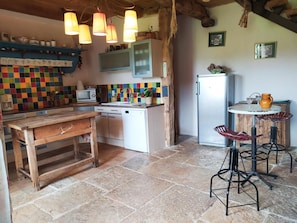 Eine Küche mit Holztisch, Geschirrspüler, Kühlschrank und farbenfroher Spritzschutz.