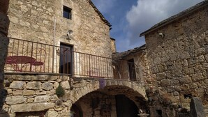 Un edificio de piedra con un balcón, un arco y un ventanal pequeño.