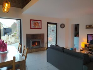 Ein Wohnzimmer mit Kamin, einer Couch, einem Esstisch mit Stühlen und einem Fernseher.