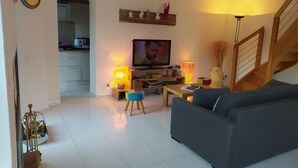 A living room with a sofa, TV, lamp, and a staircase. - La Cazelle - LE ROZIER (LE ROZIER)