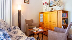 A living room with a sofa, armchairs, a wooden cabinet with books, a table with a teapot, and a lamp. - Les Hauts de Maison Rouge (VIALAS)