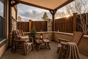 Eine überdachte Terrasse mit Holzmöbeln, einem kleinen Tisch mit Getränken und einer Steinwand.