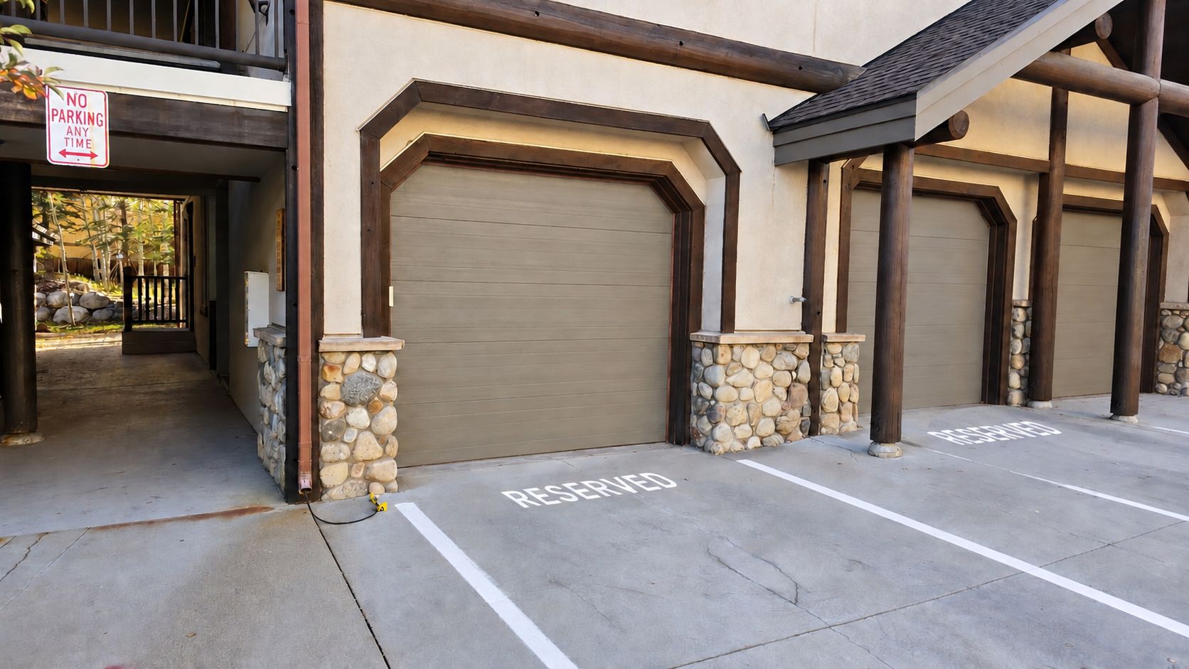 A building with a garage door, a 'No Parking Any Time' sign, and a reserved parking space.