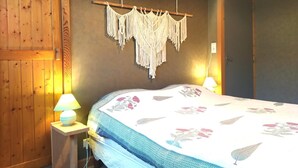 A room with a bed, wooden walls, a macrame wall hanging, and two bedside lamps. - LA DROSERA - LAJO - Gîte (LAJO)