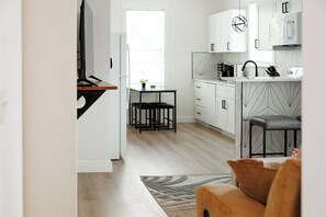 Eine moderne Küche mit weißen Schränken, einer schwarzen Arbeitsplatte und einem Essbereich mit Tisch und Stühlen.
