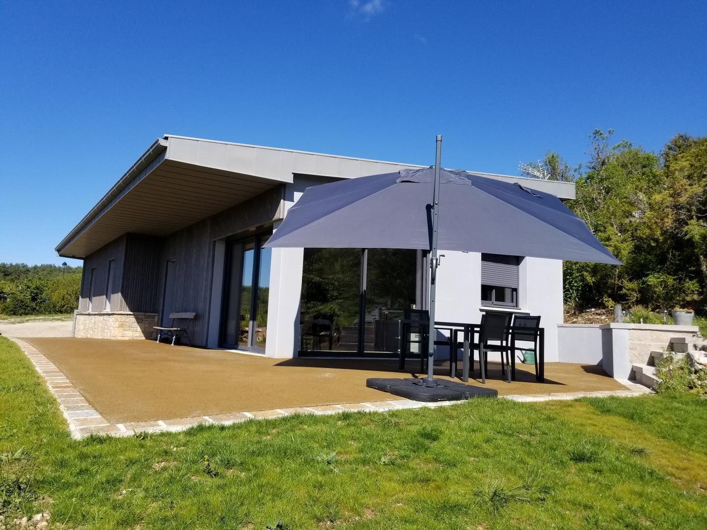 Ein modernes Haus mit einer Terrasse, einem Tisch und Stühlen.