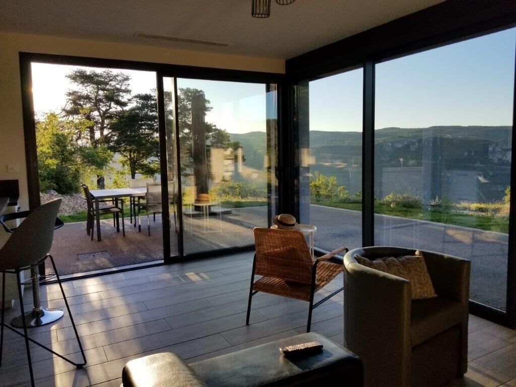 Una habitación moderna con ventanas amplias, un comedor y un conjunto de asientos.