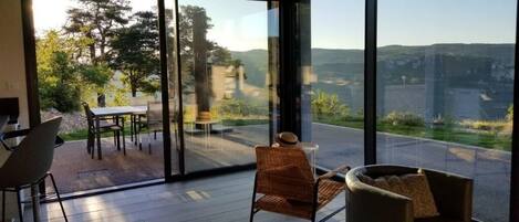 Una habitación moderna con ventanas amplias, un comedor y un conjunto de asientos.