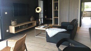 Een moderne woonkamer met een flatscreen televisie, een salontafel, een bank en een boekenkast.