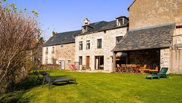 A stone building with a grassy yard, outdoor seating, and a clear sky.