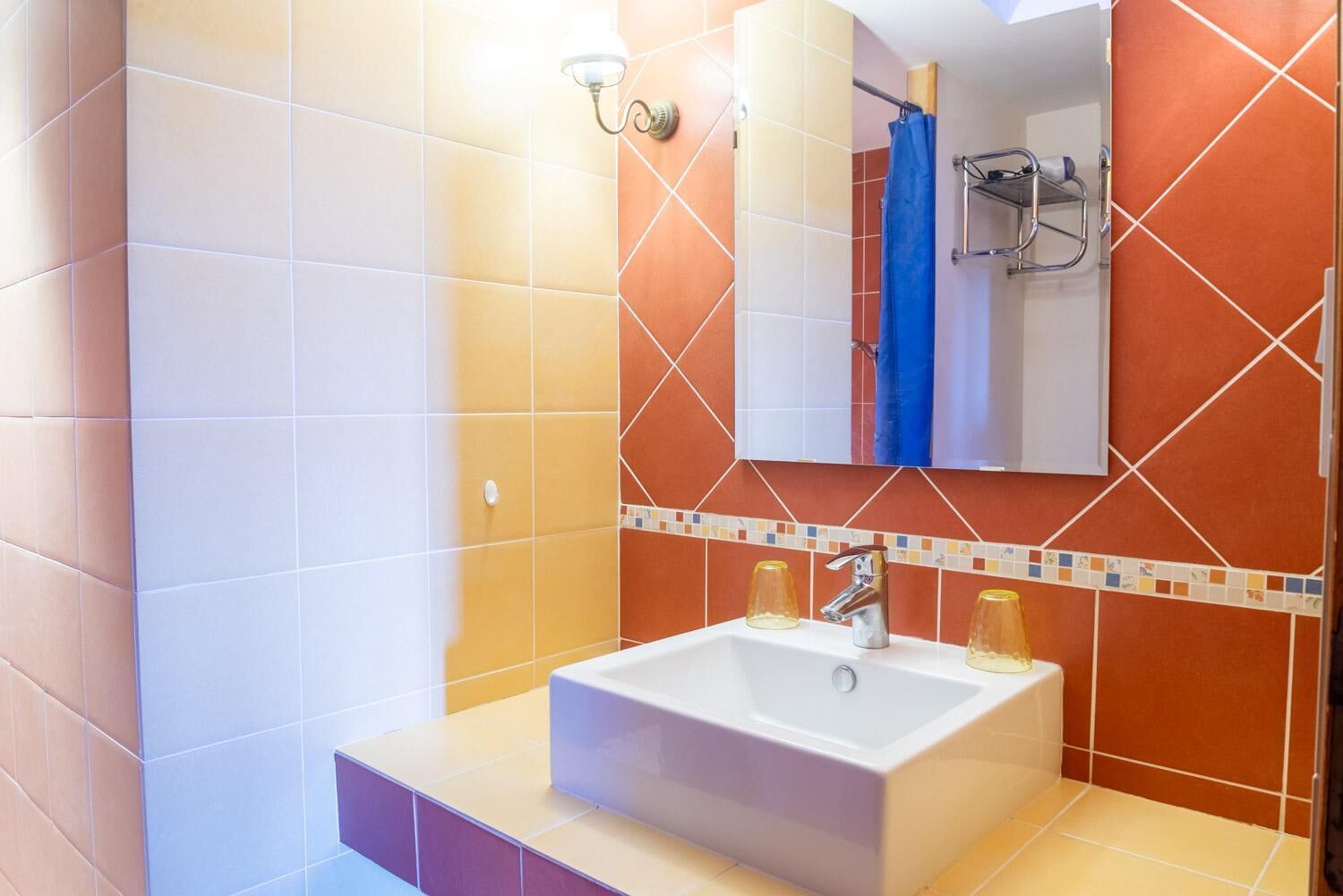 Casa de banho com lavatório branco, espelho e zona de duche.