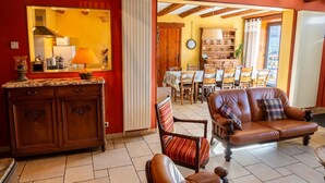 Una sala de estar con un mueble de madera, un sofá, un sillón a rayas y un comedor con una mesa y sillas.