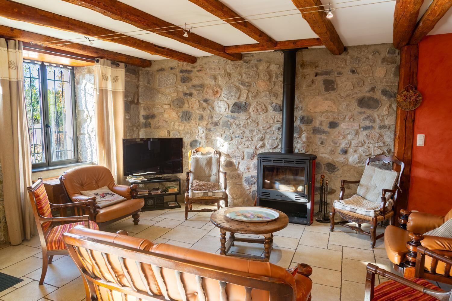 Una sala de estar acogedora con paredes de piedra, chimenea, sofás de cuero y un televisor.
