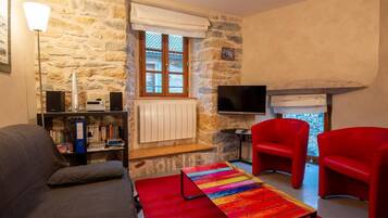 Ein Wohnzimmer mit Steinwand, Kamin, Fernseher und roten Sesseln.