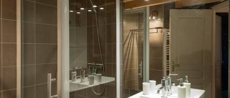 Un baño moderno con cabina de ducha de vidrio, un lavabo blanco y encimera de vidrio.