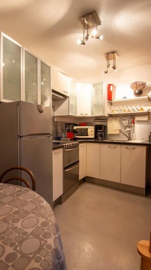 Eine kleine Küche mit Kühlschrank, Herd, Mikrowelle und Spüle.