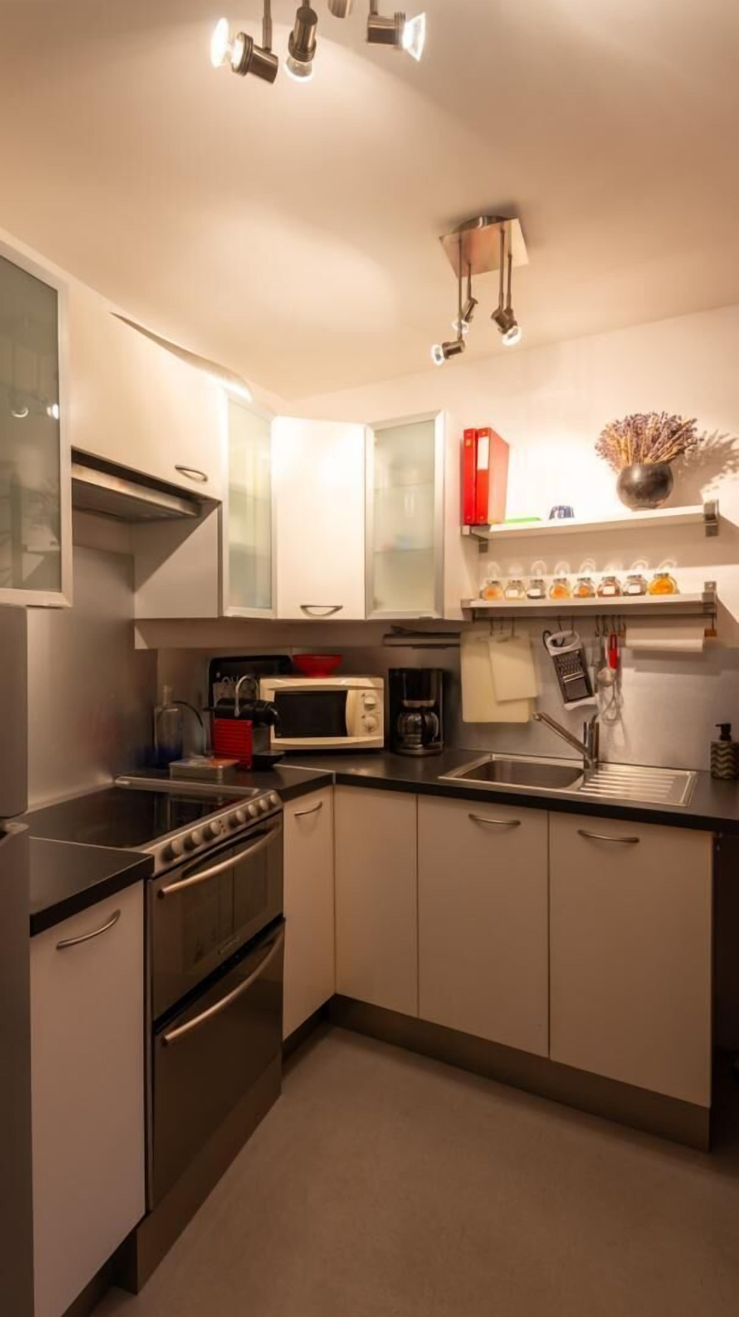 Una cocina moderna con electrodomésticos de acero inoxidable, armarios blancos y horno empotrado.