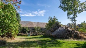Ein Steinhaus mit einem Rasen, einer Schaukel und einer großen Felsformation.