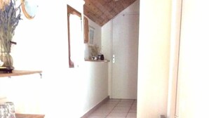 Een trap die leidt naar een kamer met een betegelde vloer, een houten plafond en een witte deur.