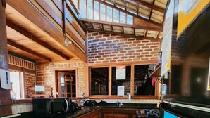 A kitchen with wooden cabinets, a tiled floor, and a brick wall.
