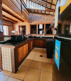 A kitchen with wooden cabinets, a tiled floor, and a brick wall.