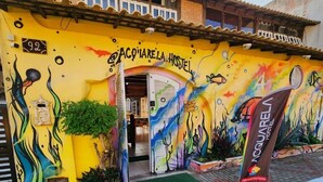 A hostel with a colorful mural, a sign reading 'ACQUAIRELA HOSTEL,' and a brick exterior.