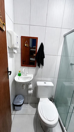 A bathroom with a toilet, sink, and glass shower enclosure.