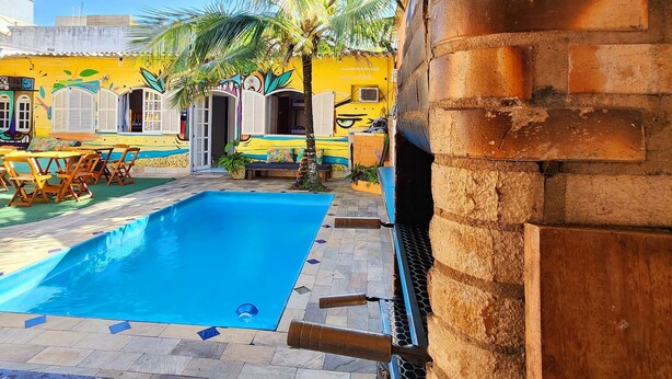 A pool area with a covered patio, a brick wall, and a building with colorful murals in the background.