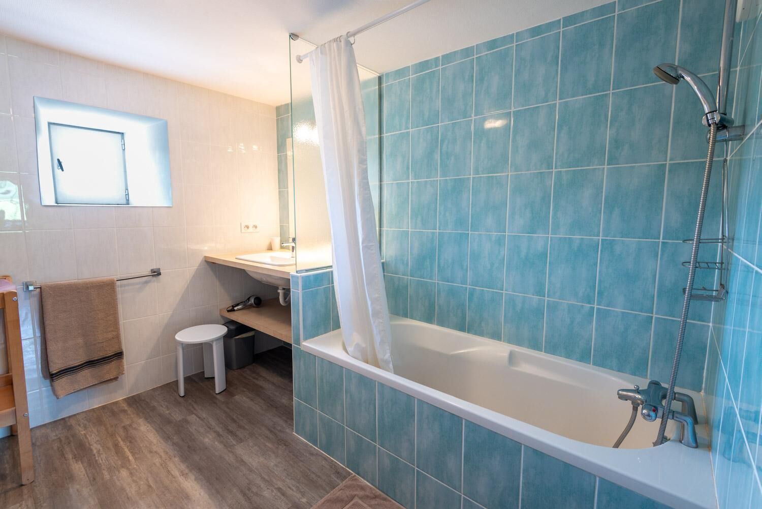A bathroom with a bathtub, shower, and a small window.